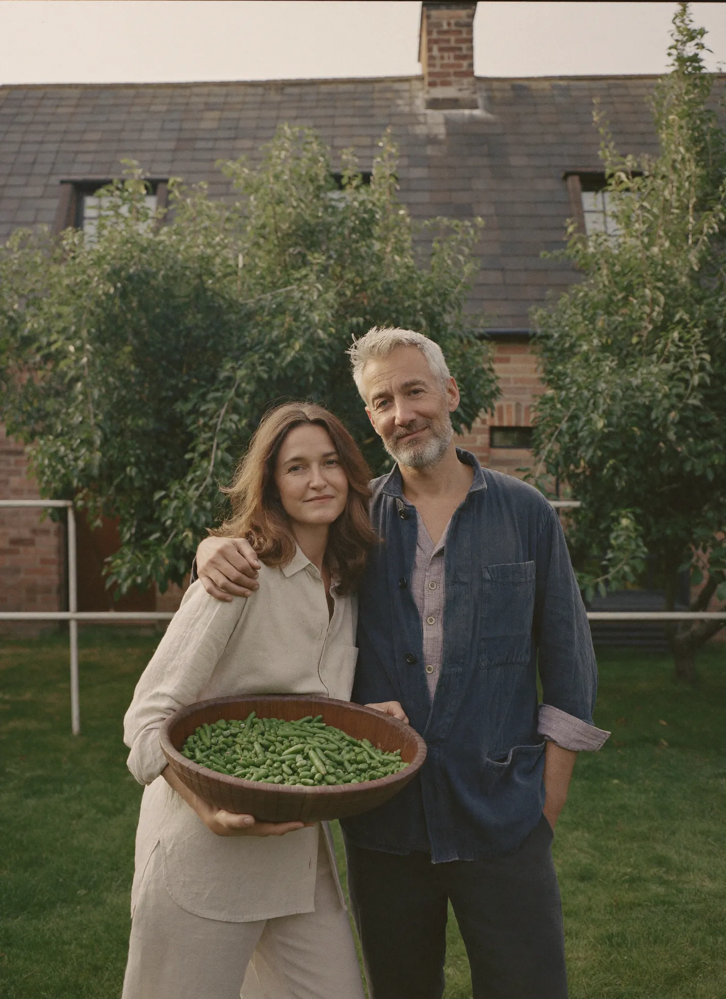 Nell and Hugo Carrow in the walled garden holding a bowl of freshly picked beans