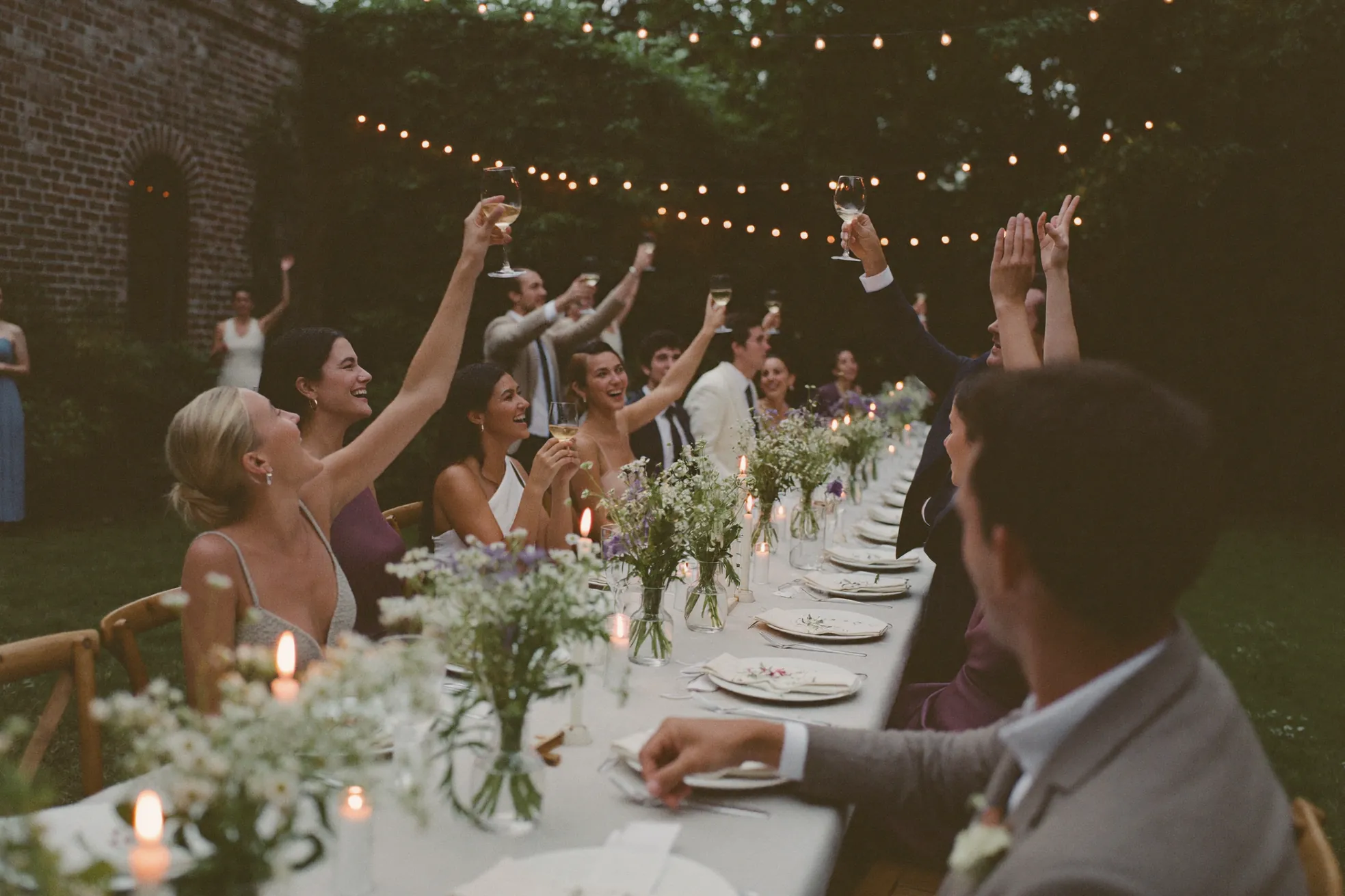 Guests raising glasses at a long table in the walled garden